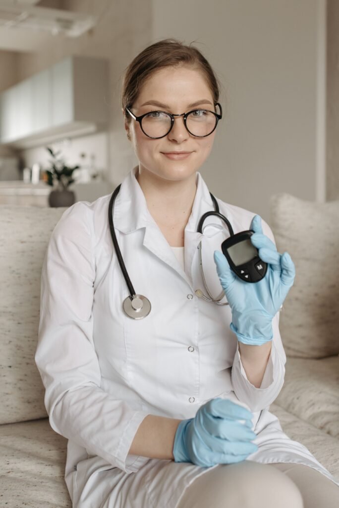A female doctor with eyeglasses and gloves showcasing a glucometer indoors