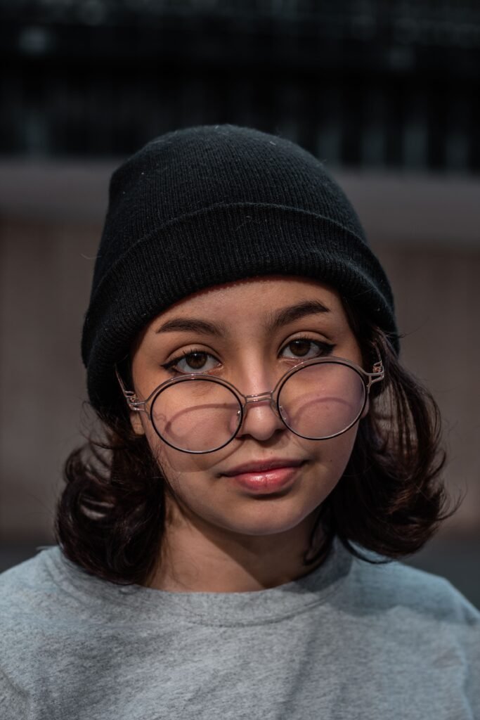 Close up portrait of a young woman wearing a beanie and eyeglasses captured during the day